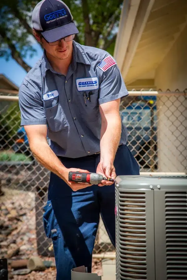 Goettl’s High Desert Mechanical technician tightening service panel screws on outdoor condenser – Prescott Valley AZ
