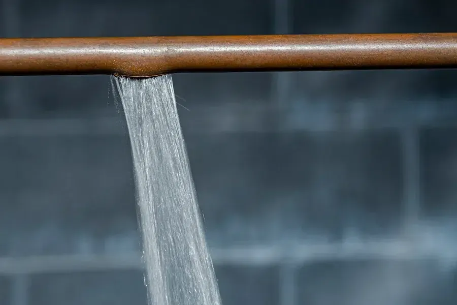 close-up of a ruptured copper pipe spraying water in home – Prescott Valley AZ